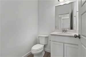 Bathroom featuring toilet, hardwood / wood-style flooring, and vanity with extensive cabinet space