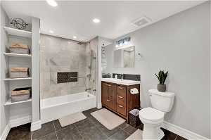 Full bathroom featuring heated tile flooring, large vanity, toilet, and tiled shower / bath