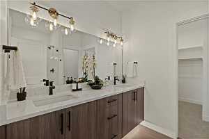 Bathroom with a shower, double sink, vanity with extensive cabinet space, and hardwood / wood-style flooring
