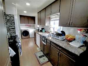 Kitchen with washing machine and clothes dryer, range, light hardwood / wood-style flooring, backsplash, and dark brown cabinets