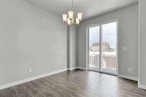 Spare room featuring an inviting chandelier and dark wood-type flooring