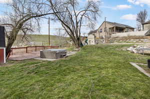 View of yard featuring a wooden deck and a hot tub