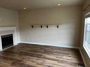 Unfurnished living room featuring a fireplace and dark wood-type flooring