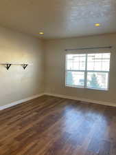 Unfurnished room with a textured ceiling and dark wood-type flooring