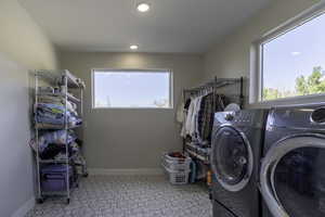 Clothes washing area featuring light tile floors and washer and clothes dryer