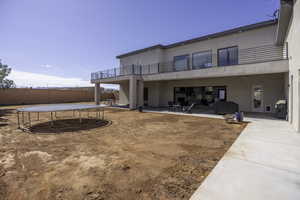 Back of house featuring a patio area, a balcony, and a trampoline