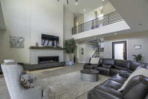 Tiled living room with ceiling fan, a tile fireplace, and a high ceiling