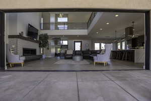 Interior space with a fireplace, a high ceiling, concrete flooring, and ceiling fan with notable chandelier