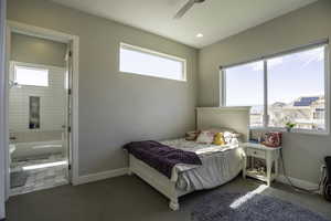 Carpeted bedroom with multiple windows, ensuite bath, and ceiling fan