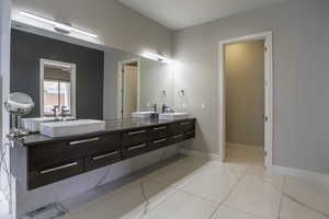 Bathroom with tile flooring, vanity with extensive cabinet space, and dual sinks