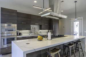 Kitchen featuring pendant lighting, stainless steel appliances, a kitchen island, and island range hood