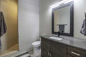 Bathroom with tile flooring, tile walls, vanity, toilet, and tiled shower