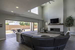 Living room featuring a tiled fireplace, a towering ceiling, tile floors, and a wealth of natural light