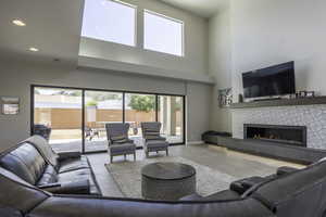 Living room featuring a towering ceiling, light tile floors, and a fireplace