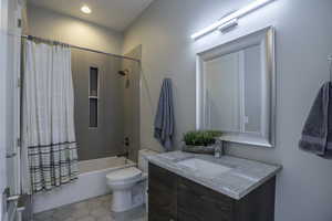 Full bathroom with tile flooring, vanity, shower / bath combination with curtain, and toilet