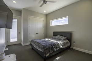 Bedroom featuring multiple windows, dark carpet, and ceiling fan