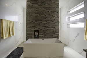 Bathroom with a bathing tub, tile flooring, and tile walls