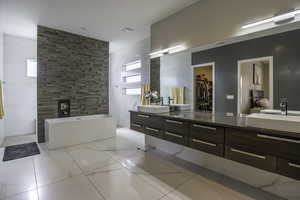 Bathroom featuring tile flooring, double vanity, a wealth of natural light, and a bath to relax in