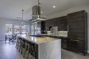 Kitchen featuring an island with sink, island range hood, a wealth of natural light, and hanging light fixtures