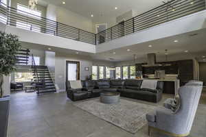 Living room featuring sink, a towering ceiling, and light tile flooring