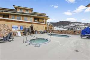 Snow covered pool featuring a mountain view and a hot tub