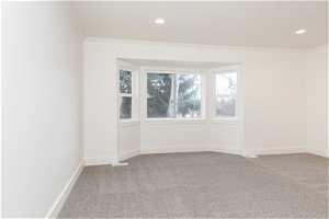 Spare room featuring ornamental molding and light carpet