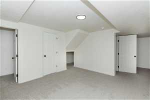Bonus room featuring a textured ceiling and light carpet