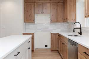 Kitchen with light hardwood / wood-style floors, tasteful backsplash, sink, and dishwasher