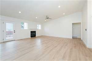 Unfurnished living room with ceiling fan, vaulted ceiling, and light hardwood / wood-style floors