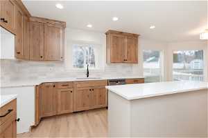 Kitchen featuring light hardwood / wood-style floors, tasteful backsplash, sink, and stainless steel dishwasher