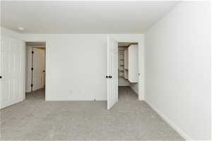 Unfurnished bedroom featuring a spacious closet and light colored carpet
