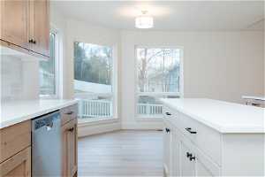 Kitchen featuring backsplash, light wood-type flooring, a center island, dishwasher, and white cabinetry