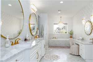 Bathroom with tile floors, a relaxing tiled bath, vanity, and a chandelier