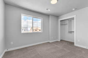 Unfurnished bedroom with carpet, a closet, and a textured ceiling