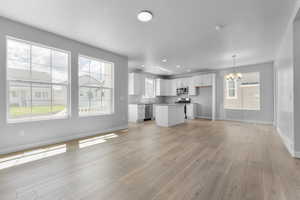 Unfurnished living room with a chandelier and light hardwood / wood-style floors