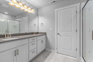 Bathroom with an enclosed shower, tile flooring, double sink, and oversized vanity