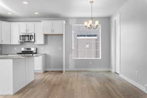 Kitchen with white cabinets, light hardwood / wood-style flooring, and range