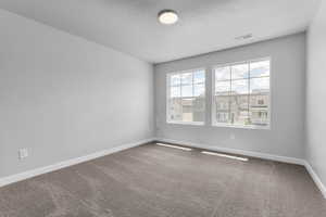 Carpeted spare room featuring a textured ceiling