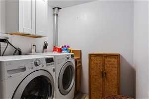Washroom with cabinets, washer hookup, light hardwood / wood-style floors, and washer and dryer