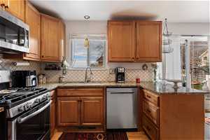 Kitchen with plenty of natural light, appliances with stainless steel finishes, sink, and light stone countertops
