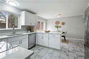 North unit Kitchen with kitchen peninsula, stainless steel appliances, light tile floors, tasteful backsplash, and white cabinetry