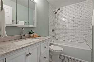 North unit Full bathroom with tile flooring, vanity, toilet, and tiled shower / bath combo