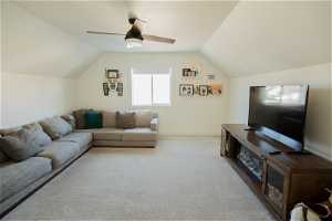 Carpeted living room featuring ceiling fan and vaulted ceiling