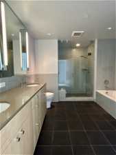 Full bathroom with backsplash, vanity, tile floors, separate shower and tub, and toilet