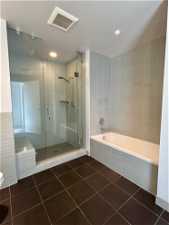 Bathroom with toilet, tile flooring, and shower with separate bathtub