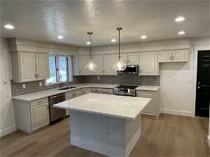 Kitchen featuring white cabinets, stainless steel appliances, and light wood-type flooring