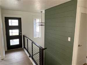 Doorway with a textured ceiling, a wealth of natural light, and hardwood / wood-style flooring