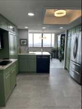 Kitchen with a tray ceiling, sink, cabinetry, stainless steel appliances, and light tile flooring