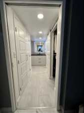 Hall to walk-in closet with a pocket door (on left) and light tile flooring in Primary Bedroom