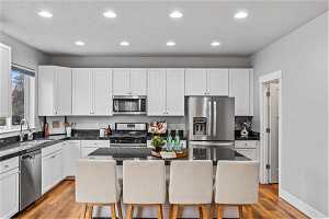 Kitchen with a breakfast bar, light wood-type flooring, appliances with stainless steel finishes, and a kitchen island